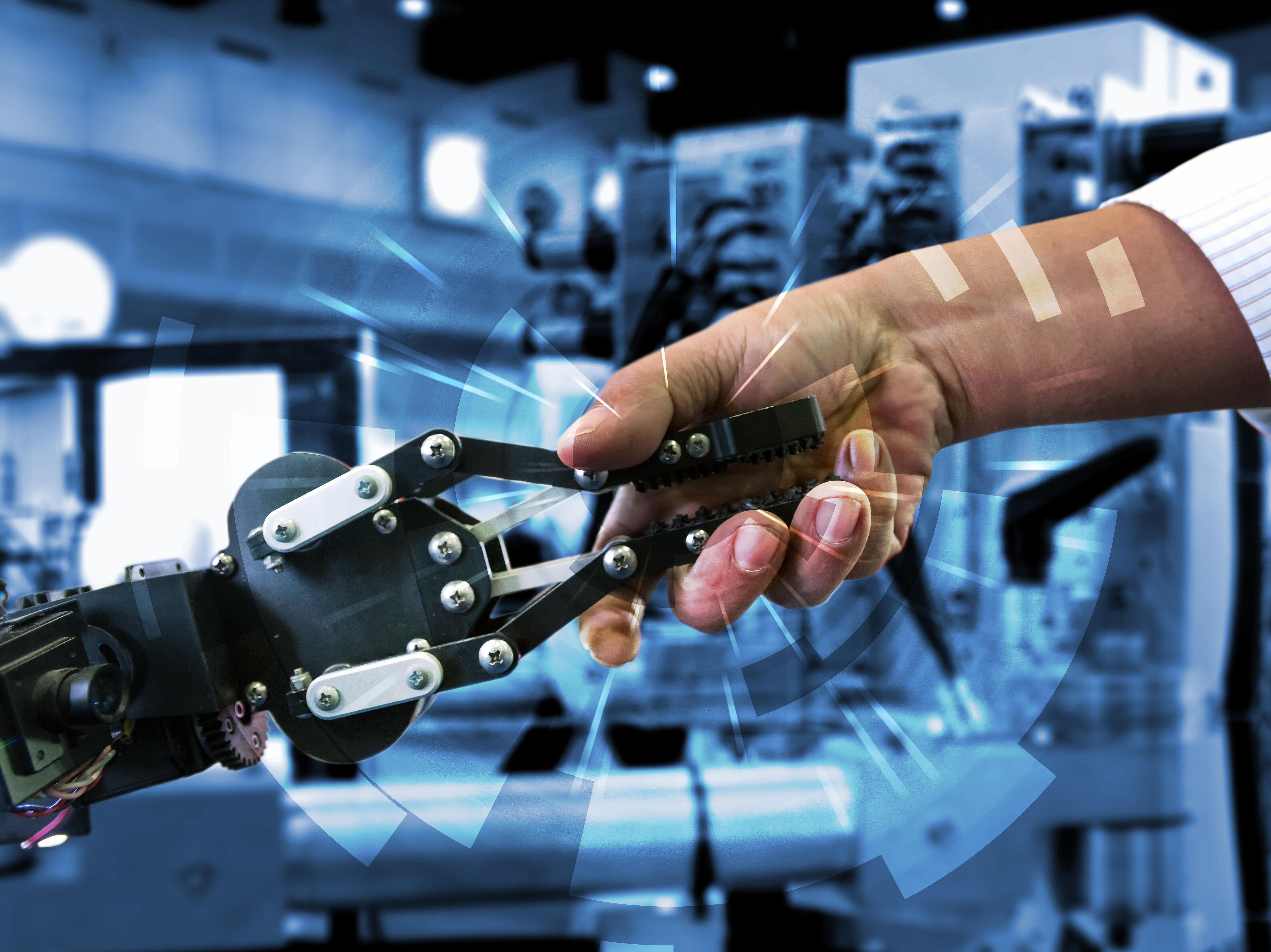 Roboter und ein Mensch halten Hand mit Handschlag vor einem abstrakten technologischen Hintergrund.