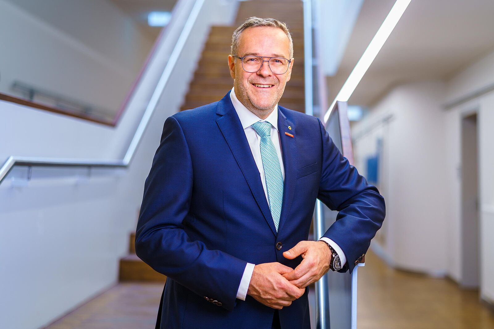 Präsident der Handwerkskammer Dresden steht im Foyer am Fußende der Treppe im Gebäude njumii - Das Bildungszentrum des Handwerks.