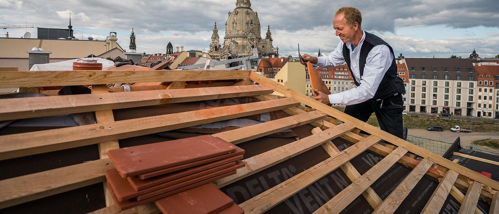 Auf einem Dach-Rohbau steht eine Person und führt Arbeiten aus.