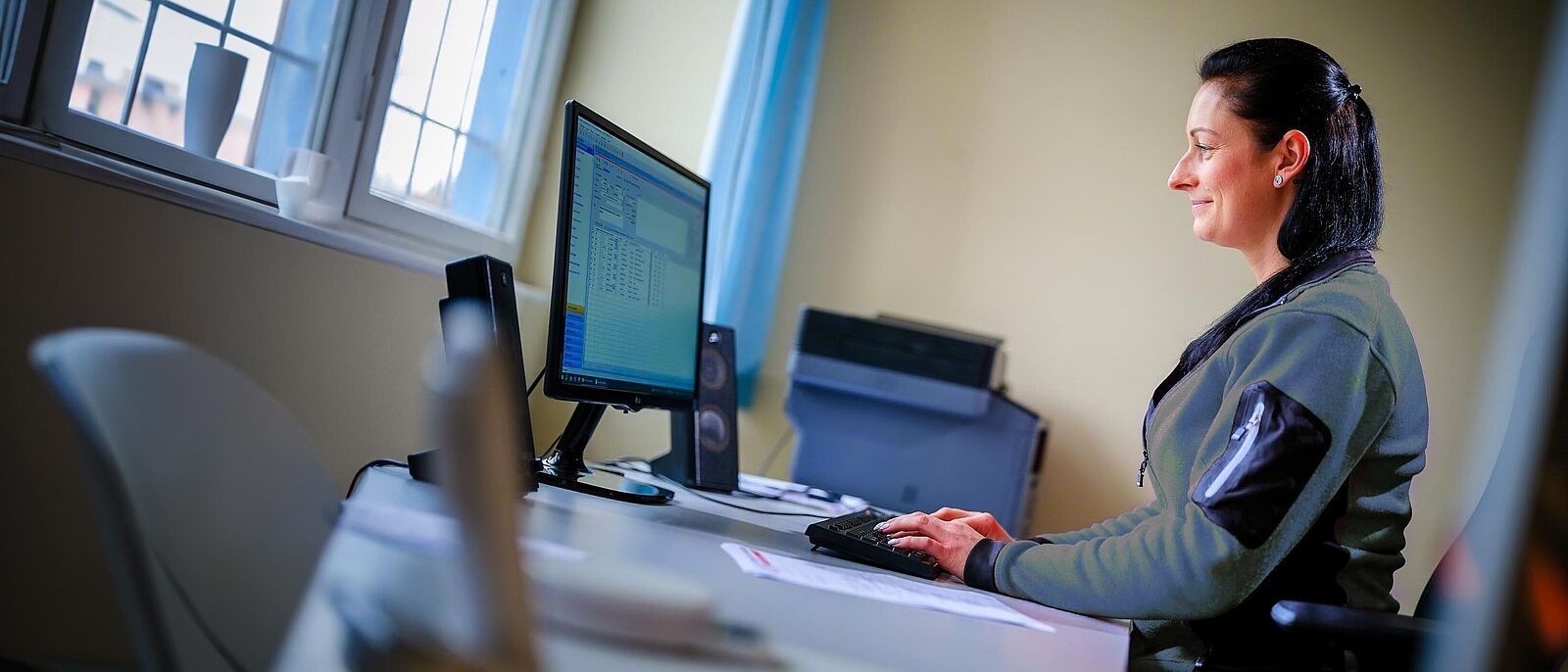 Eine Person sitz an einem Schreibtisch vor einem PC und erstellt eine Abrechnung.