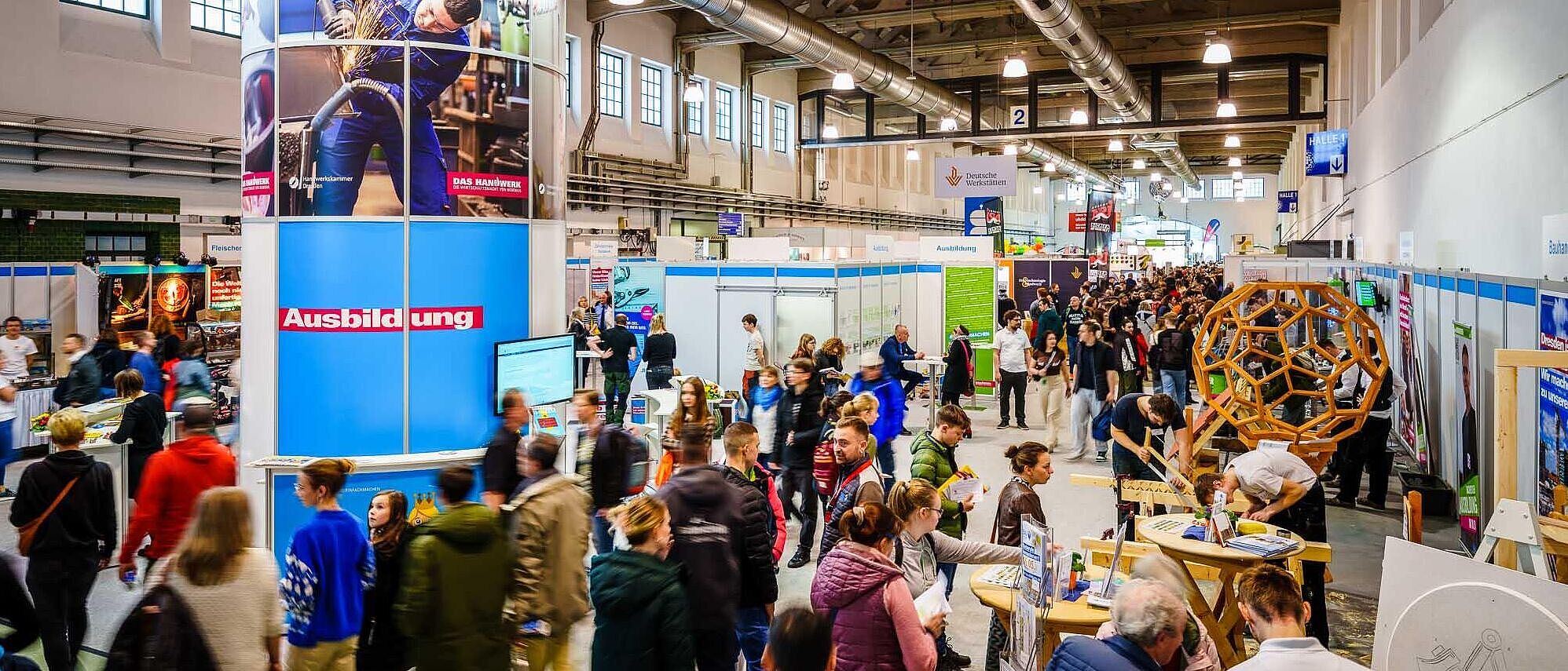 Blick in die Messehalle mit seinem Besucherstrom, im Vordergrund der Gemeinschaftsstand der Handwerkskammer mit seinem Branding.