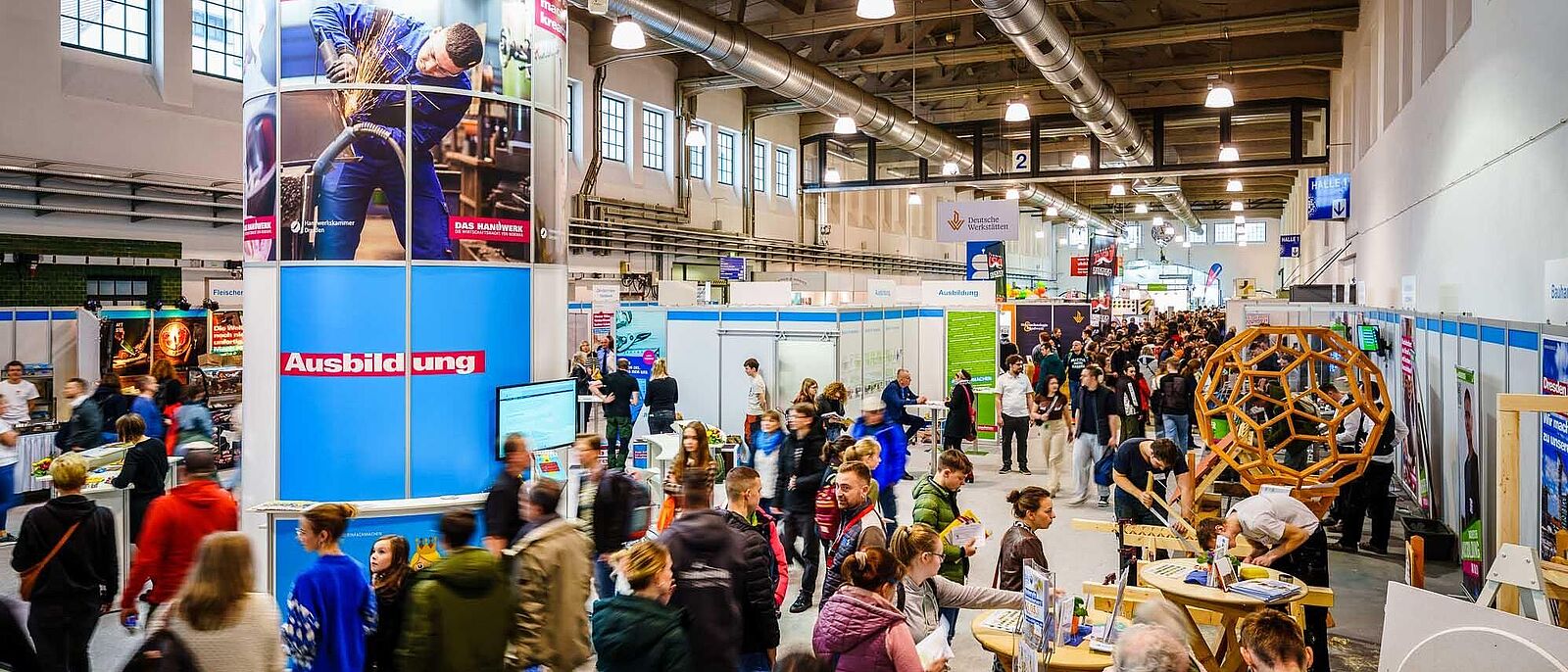 Blick in die Messehalle mit seinem Besucherstrom, im Vordergrund der Gemeinschaftsstand der Handwerkskammer mit seinem Branding.