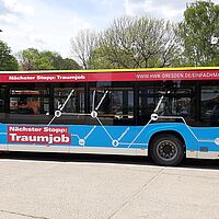 Ein Linienbus foliert mit einem regionalen Motiv der Imagekampagne, in blau, weiß rot gehalten. Der Spruch \"Nächster Stopp: Traumjob\" ist darauf zu sehen.