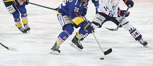 Auf einer Eisfläche spielen mehrere Personen Eishokey.