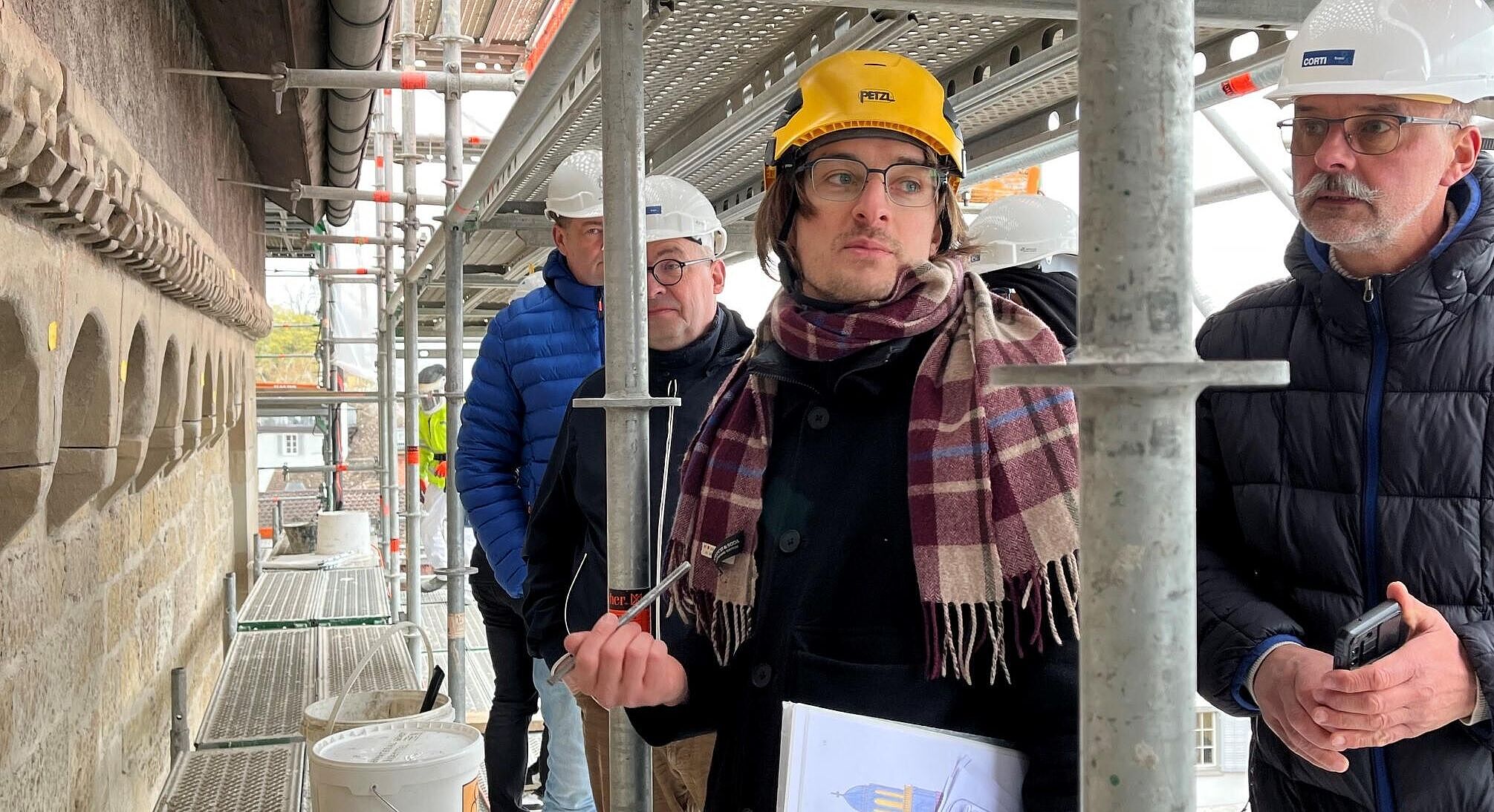 Restaurierung trifft Innovation: Handwerksbetriebe auf Messeerkundungsreise in Zürich Portraitaufnahme von zwei Personen auf einem Baugerüst Großmünster.