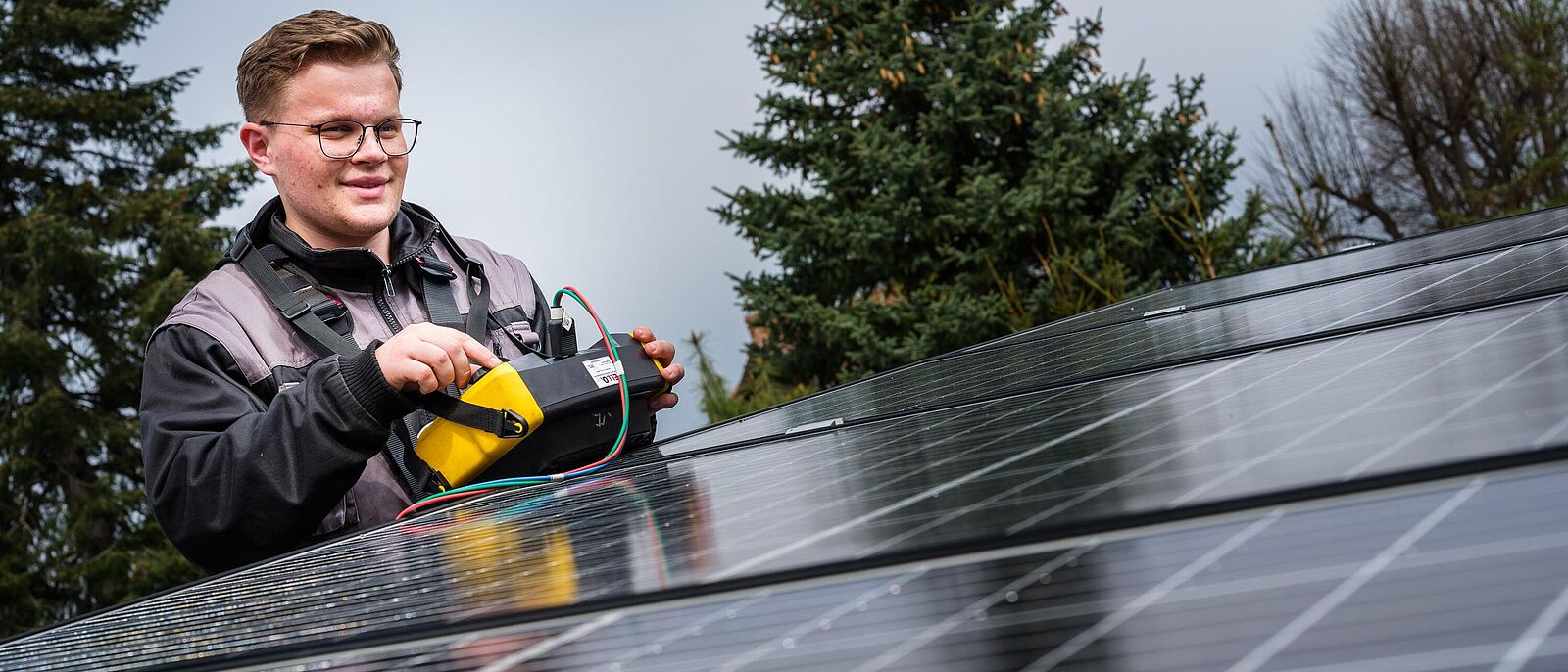 Ausbildungsatlas Insider: Elektroniker Impressionen vom Insidertreff – Eine Person steht steht zwischen mehreren Solarpanel und führt technische Prüfungen durch.