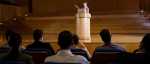 Weibliche Geschäftsführerin die in einem Konferenzsaal eine Präsentation hält - Zum Beitrag