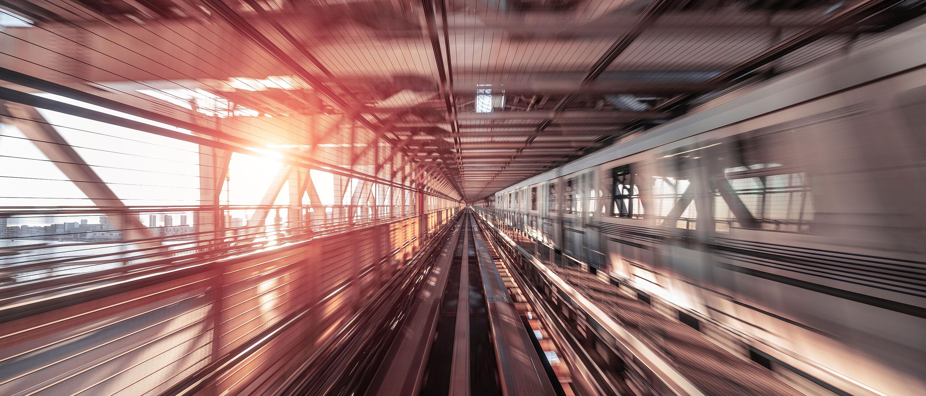 Foto mit Motion Blur Effekt eines Zuges welches über eine Stahlbrücke fährt.
