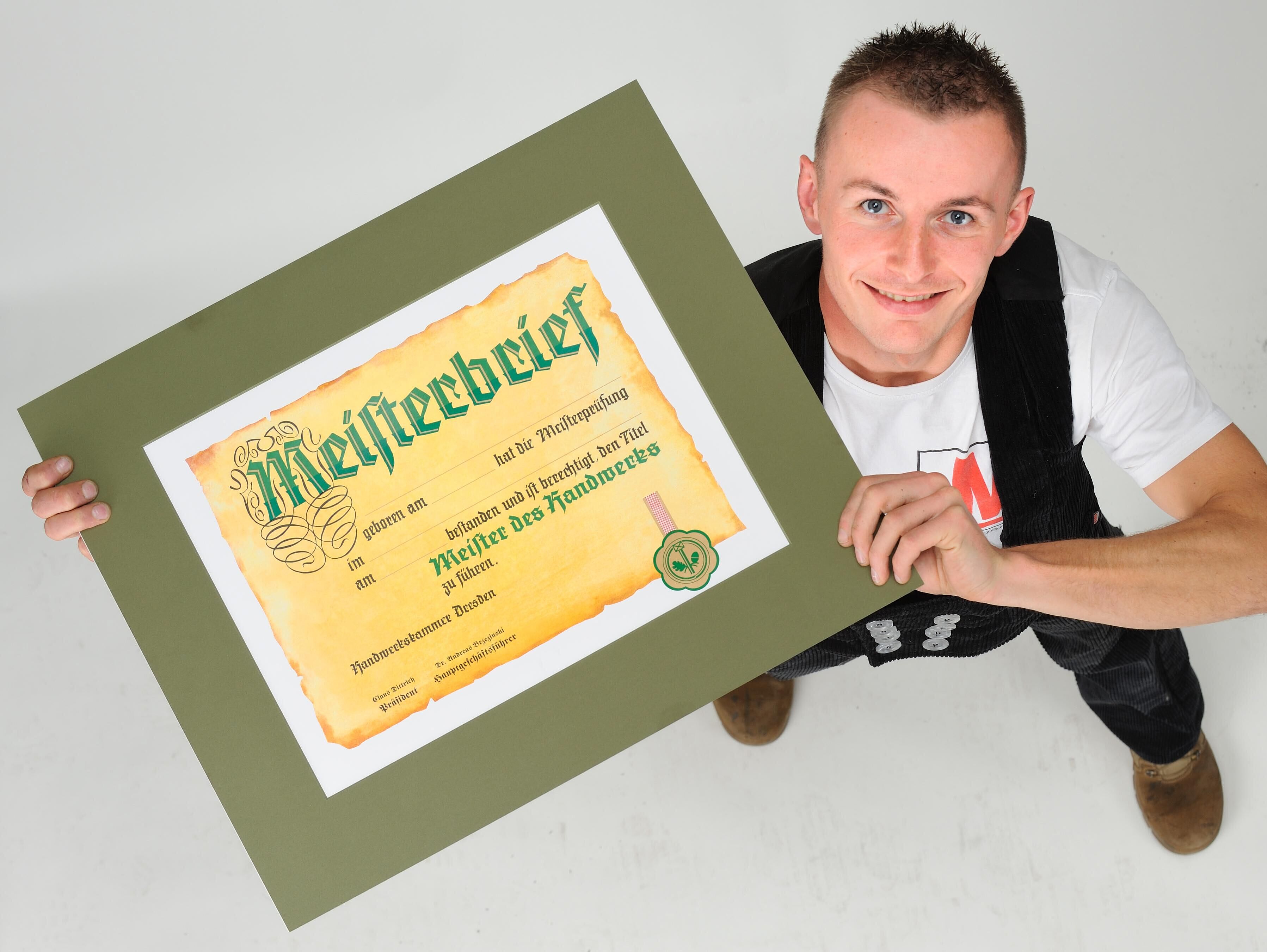 Draufsicht: Dachdeckermeister hält stolz seinen Meisterbrief in den Händen