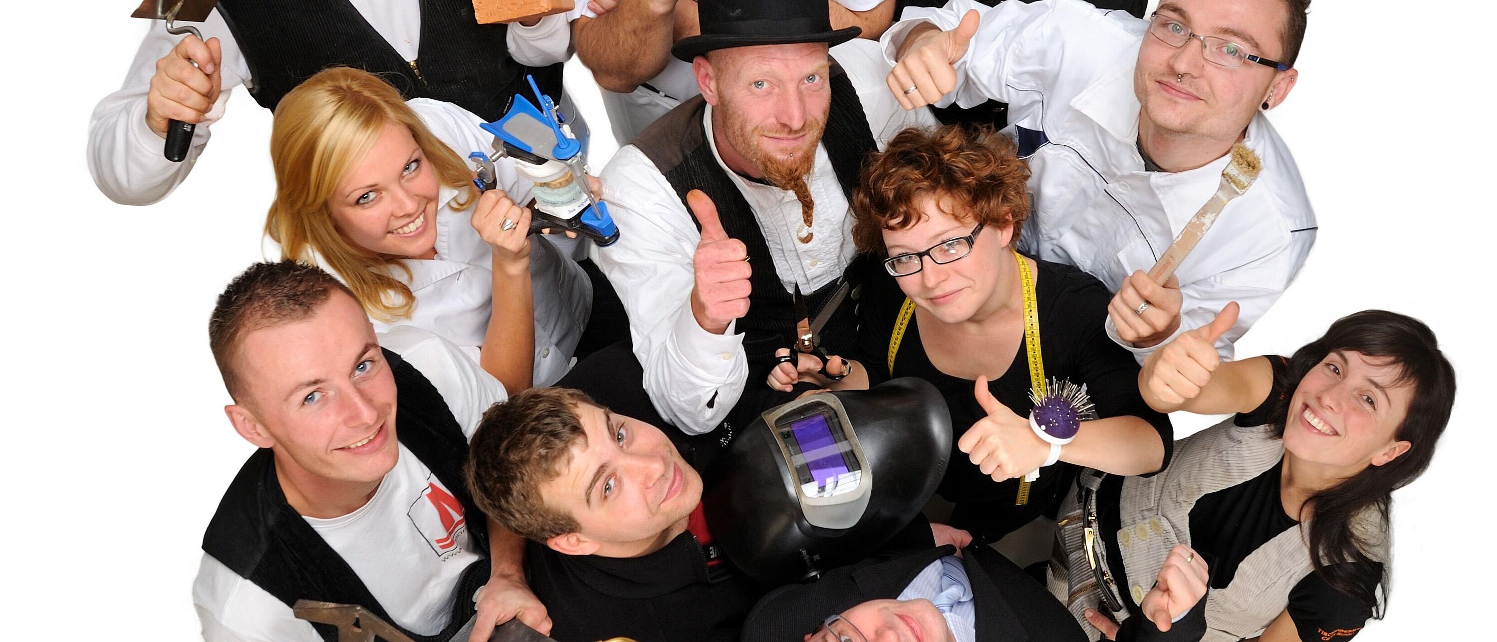 Gruppenbild von Handwerksberufen Blick von oben auf eine Personengruppe in klassischer Handwerksberufsbekleidung die im Kreis stehen und nach oben schauen.
