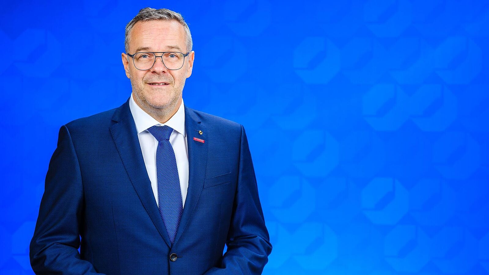 Dachdeckermeister Jörg Dittrich, Präsident der Handwerkskammer Dresden Dachdeckermeister Jörg Dittrich, Präsident der Handwerkskammer Dresden steht vor einer blauen Logo-Wand der Handwerkskammer Dresden
